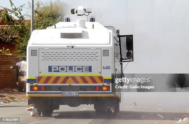 South African Police use a water cannon to disperse school children demonstrating during the bail application of hip hop artist Molemo Maarohanye,...
