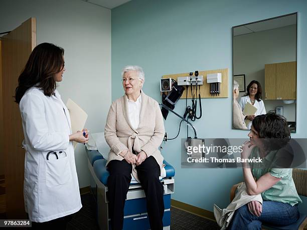 mature female patient in exam room with doctor - leanincollection stock pictures, royalty-free photos & images