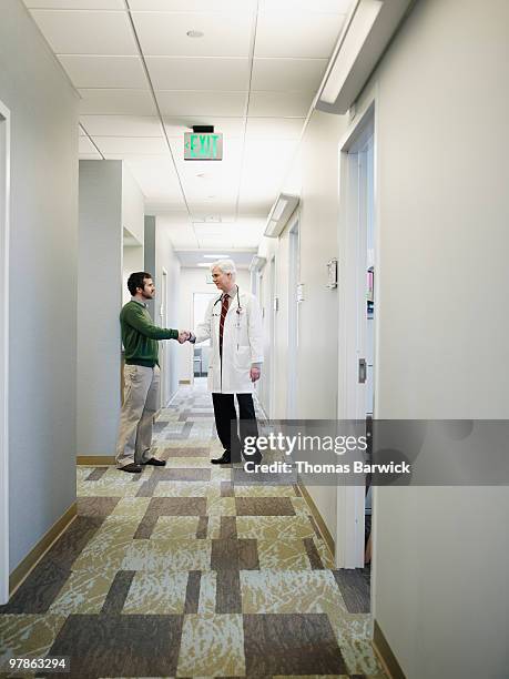 male doctor shaking hands with patient in clinic - doctor giving good news stock pictures, royalty-free photos & images