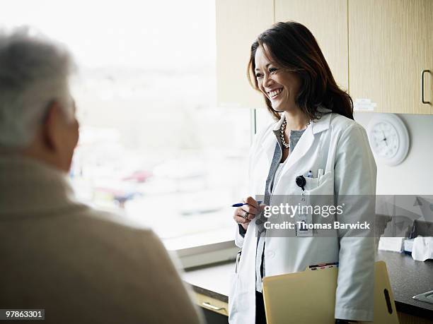 doctor in discussion with mature female patient - doctor lab coat stock pictures, royalty-free photos & images