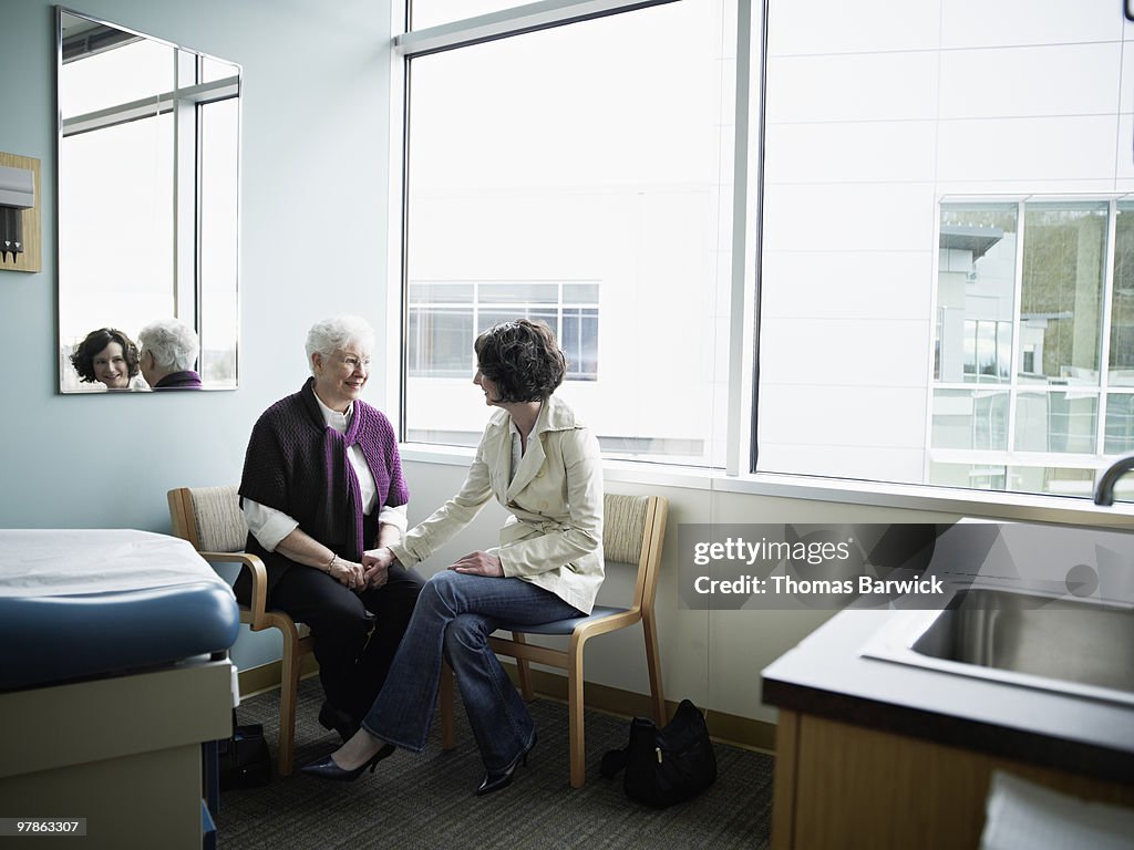 Mature mother and daughter sitting in exam room