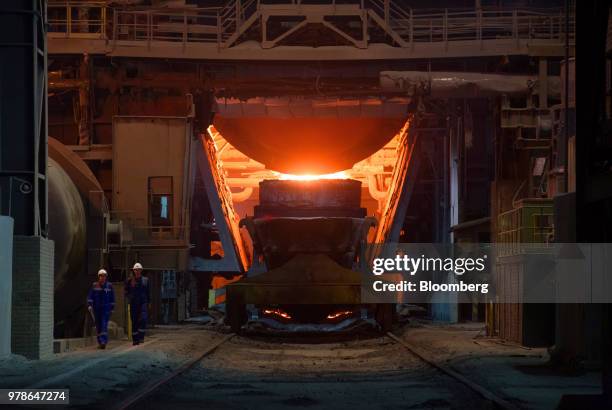 Workers pass a giant ladle filled with finished molten steel the converter shop at the Novolipetsk Steel PJSC plant, operated by NLMK Group, in...