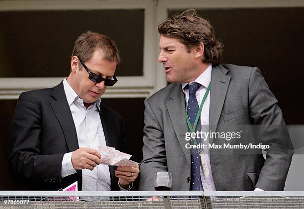 Matthew Freud checks his Tote betting slips as he talks with race horse trainer Charlie Brooks on 'Ladies Day' of the Cheltenham Horse Racing...