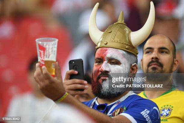 Fan sporting a viking helmet takes a photo of his beer before the Russia 2018 World Cup Group H football match between Poland and Senegal at the...