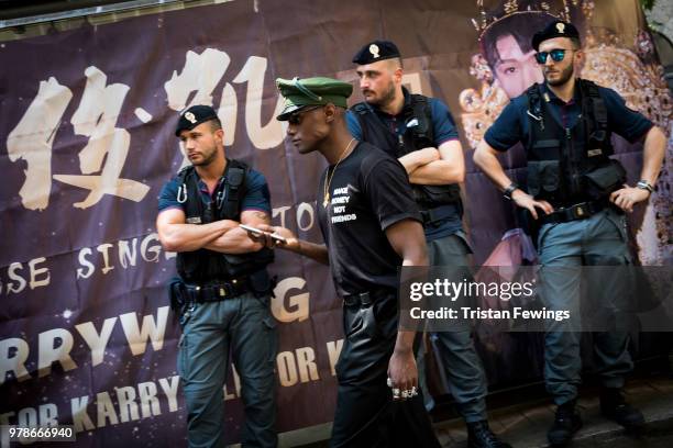 Man walks in front of police men outside the Dolce & Gabbana show during Milan Men's Fashion Week Spring/Summer 2019 on June 16, 2018 in Milan, Italy.