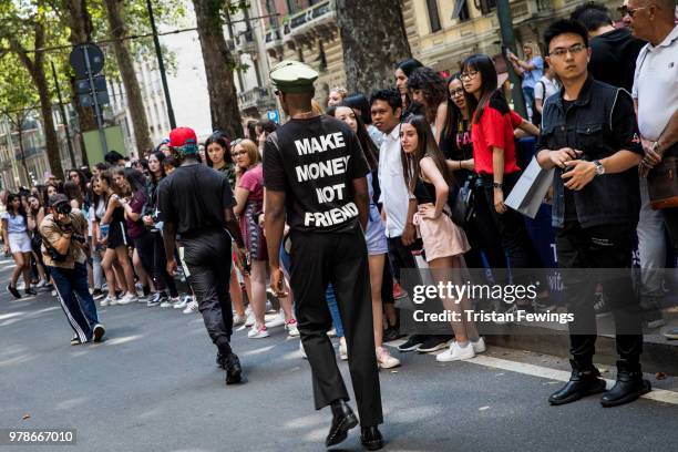 People are watching a street style photographer working outside the Dolce & Gabbana show during Milan Men's Fashion Week Spring/Summer 2019 on June...