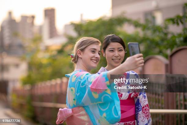multi-ethinic group of friends in yukata taking picture on slope - japan tourism stock pictures, royalty-free photos & images