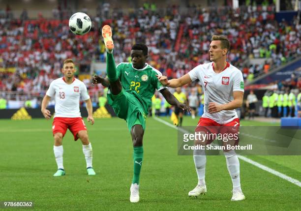 Moussa Wague of Senegal controls the ball under pressure from Arkadiusz Milik of Poland during the 2018 FIFA World Cup Russia group H match between...