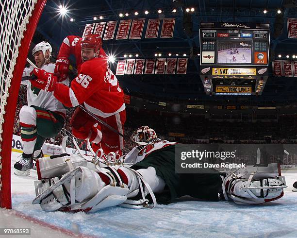 Tomas Holmstrom of the Detroit Red Wings is knocked down next to Josh Harding of the Minnesota Wild during an NHL game at Joe Louis Arena on March...