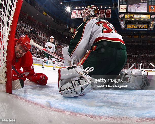 Tomas Holmstrom of the Detroit Red Wings is knocked down next to Josh Harding of the Minnesota Wild during an NHL game at Joe Louis Arena on March...