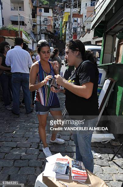 An unidentified resident of Dona Martha shantytown in Rio de Janeiro, Brazil, asks a member of a human rights defense organization about their new...