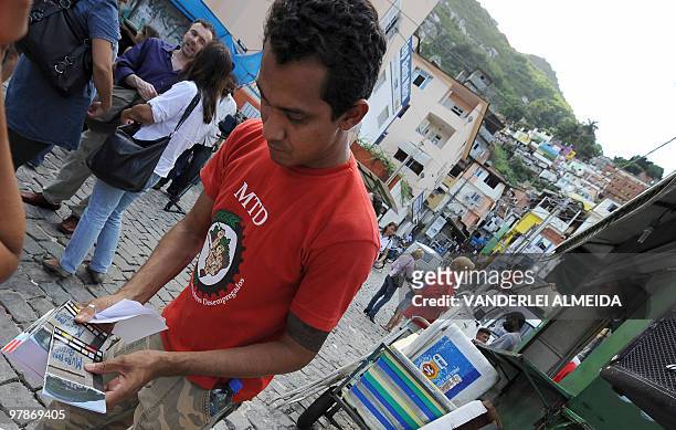 An unidentified resident of Dona Martha shantytown in Rio de Janeiro, Brazil, picks up from a member of a human rights defense organization a few...