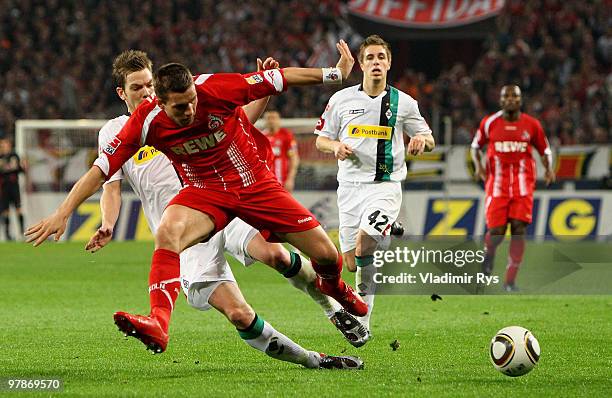 Lukas Podolski of Koeln is challenged by Thorben Marx of Moenchengladbach during the Bundesliga match between 1. FC Koeln and Borussia...