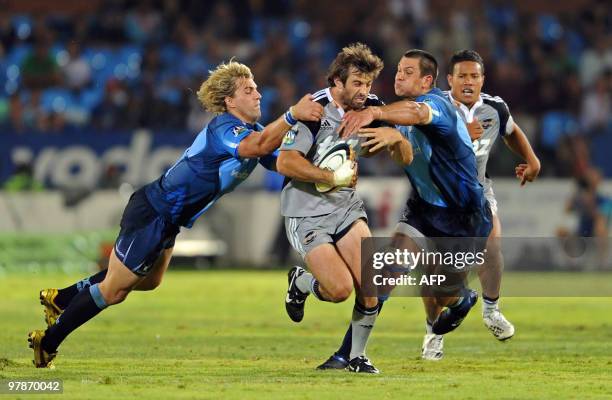 Conrad Smith of the Huricanes is tackled by Wynand Olivier and Pierre Spies of the Bulls with Alapati Leiua of the Huricanes in support during the...