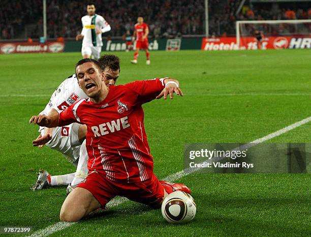 Lukas Podolski of Koeln falls after a battle with Thorben Marx of Moenchengladbach during the Bundesliga match between 1. FC Koeln and Borussia...