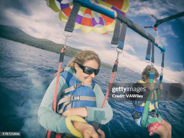 mother and 9 year old son parasail over beautiful lake tahoe, california in early summer - parasailing stock pictures, royalty-free photos & images
