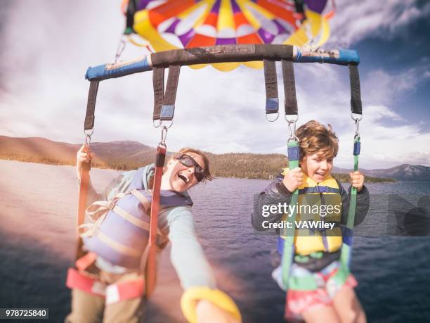 mother and 9 year old son parasail over beautiful lake tahoe, california in early summer - lake tahoe stock pictures, royalty-free photos & images