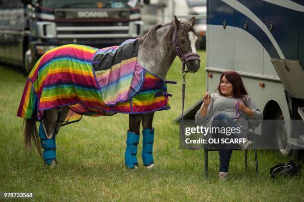 Woman sits with a horse adjacent to a showjumping ring on the first day of The Royal Cheshire County Show at Tabley, near Knutsford, northern England...