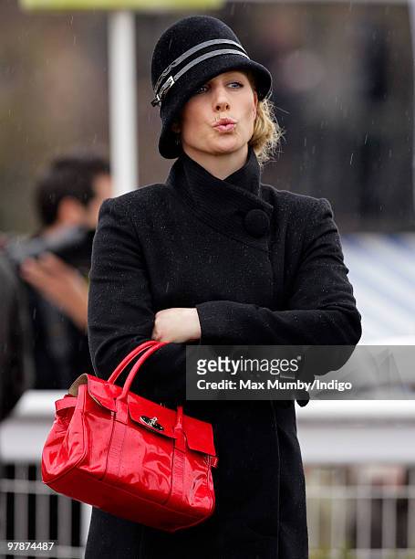 Zara Phillips pulls a face as she gets caught in a rain shower whilst watching the Cheltenham Gold Cup contenders parade prior to the race on day 4...