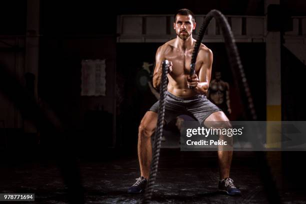 young man doing battle rope exercise - cross training stock pictures, royalty-free photos & images