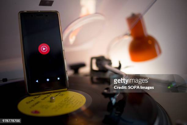 In this photo illustration, the YouTube Music application seen displayed on an Android Sony smartphone next to a vinyl record player.