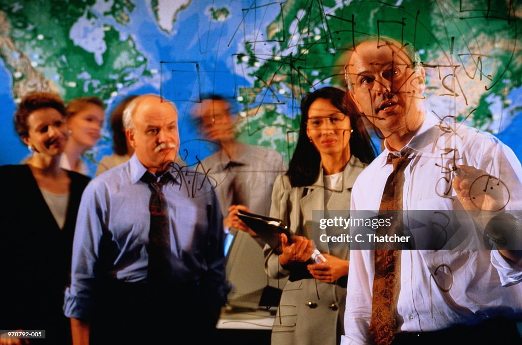 Business executives in meeting, view through transparent wipe board