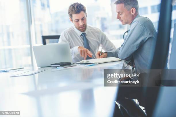 two businessmen meeting with technology. one man has a laptop computer. - ceo speaking stock pictures, royalty-free photos & images