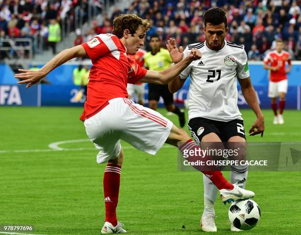 Egypt's forward Mahmoud 'Trezeguet' Hassan fights for the ball with Russia's defender Mario Fernandes during the Russia 2018 World Cup Group A...