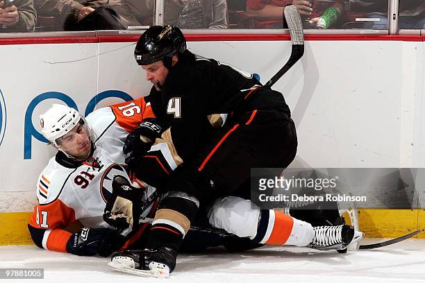 Aaron Ward of the Anaheim Ducks gets tangled up alongside the boards with John Tavares of the New York Islanders during the game on March 19, 2010 at...