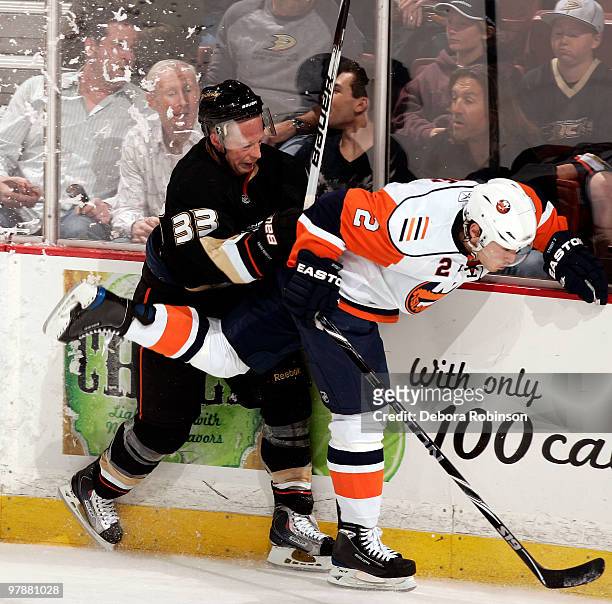 Jason Blake of the Anaheim Ducks checks Mark Streit of the New York Islanders into the boards during the game on March 19, 2010 at Honda Center in...
