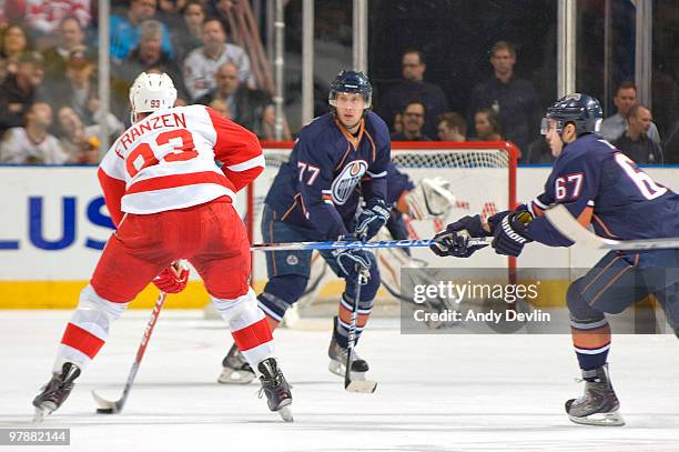 Johan Franzen of the Detroit Red Wings carries the puck towards a defending Tom Gilbert and Gilbert Brule of the Edmonton Oilers at Rexall Place on...