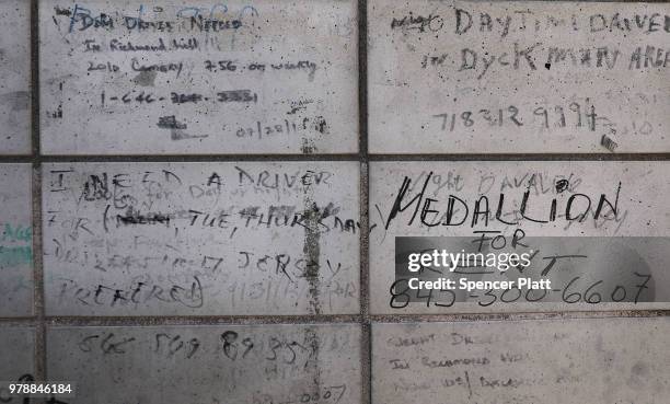 Notices for taxi drivers are written on a wall at a taxi waiting area at John F. Kennedy Airport on June 19, 2018 in New York City. Following the...