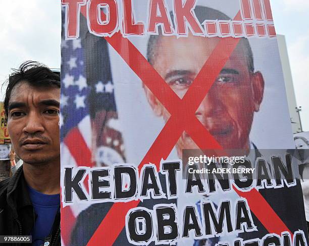 An Indonesian labourer from 'Front Perjuangan Rakyat' holds a banner reading 'Reject Obama coming to Indonesia' during a protest against a potential...