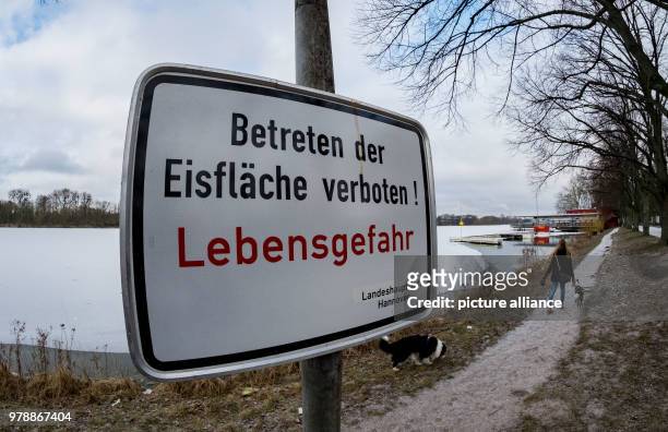 February 2018, Germany, Hanover: The sign reads 'Betreten der Eisflaeche verboten! Lebensgefahr' . Despite minus five degrees the lake is not...