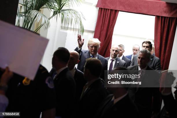 President Donald Trump, center, waves as Democratic members of congress demonstrate after a House Republican conference meeting on immigration...