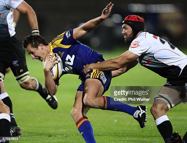 Michael Hobbs of the Highlanders is tackled by Jacques Botes of the Sharks during the round six Super 14 match between the Highlanders and the Sharks...