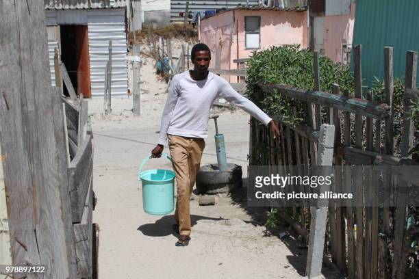 February 2018, South Africa, Cape Town, Khayelitsha: Anele Goba who lives in the Khayelitsha slum area outside Cape Town, has to carry water from a...