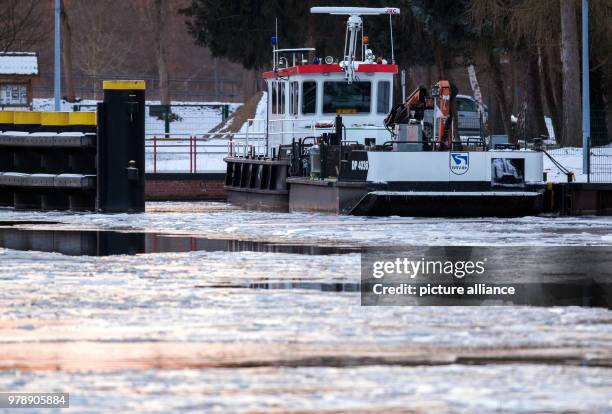 February 2018, Germany, Witzeeze: A working vessel lies in the ice at the Elbe-Luebeck Canal near the Witzeeze sluice at sunset. The canal is almost...