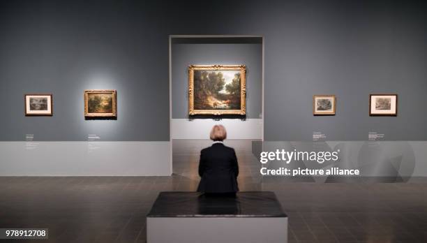 March 2018, Germany, Hamburg: A woman looks at the work "Forest scene with cows by a pond" by Thomas Gainsborough at the exhibition "Thomas...
