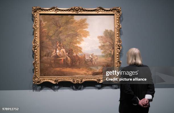 March 2018, Germany, Hamburg: A woman looks at the work "Forest scene with carriage" by Thomas Gainsborough at the exhibition "Thomas Gainsborough -...