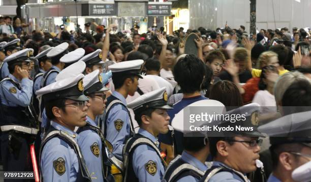 Police officers stand guard in Tokyo's Shibuya entertainment district in the small hours of June 20 as football fans celebrate Japan's victory over...