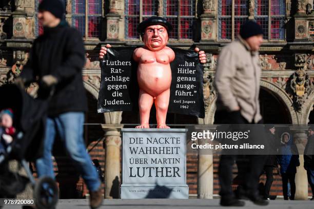 Passers-by walking by a statue of Martin Luther erected at the market square in Bremen, Germany, 01 March 2018. The statue shows a naked Martin...