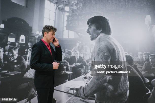 March 2018, Germany, Wolfsburg: The director of the art museum, Ralf Beil, on his phone at the exhibition "Robert Lebeck 1968". In the background is...