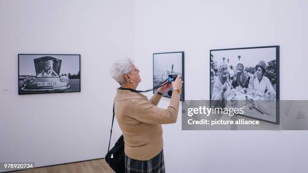 March 2018, Germany, Wolfsburg: A woman visiting the exhibition 'Robert Lecke 1968'. In the background are photographs from the series 'Das Glueck...