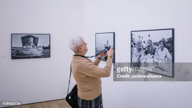 March 2018, Germany, Wolfsburg: A woman visiting the exhibition 'Robert Lecke 1968'. In the background are photographs from the series 'Das Glueck...