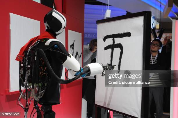 March 2018, Spain, Lisbon: A robot from the Japanese Telekom company Docomo paints a picture at the Mobile World Congress 2018 by copying the...