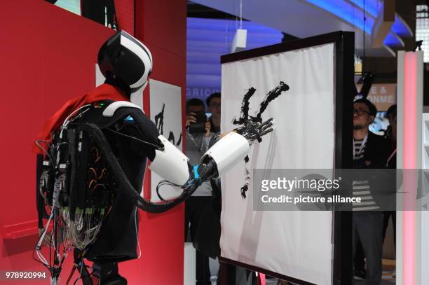 March 2018, Spain, Lisbon: A robot from the Japanese Telekom company Docomo paints a picture at the Mobile World Congress 2018 by copying the...
