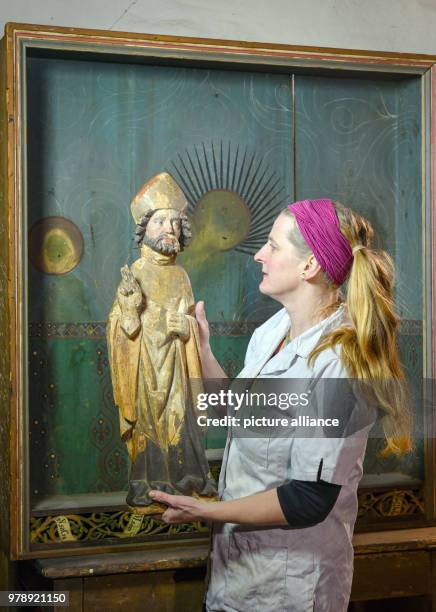 February 2018, Germany, Neuzelle: The conservator Dorothee Schmidt-Breitung holds a historian holy figure from the 15th century in front of the...