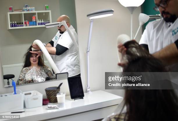 March 2018, Germany, Berlin: Naram Shakra kills the head lice of the customer Monika Beloch at the anti lice salon "Bye bye Laeuse" with hot air....