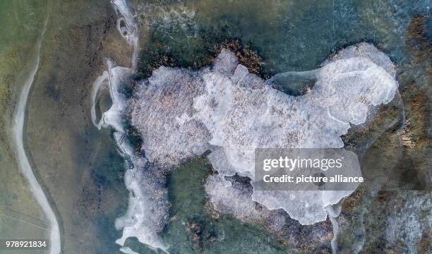 March 2018, Germany, Grossraeschen: The flat shore areas of the Grossraeschen lake are covered in ice . The brown coal open pit has been flooded for...